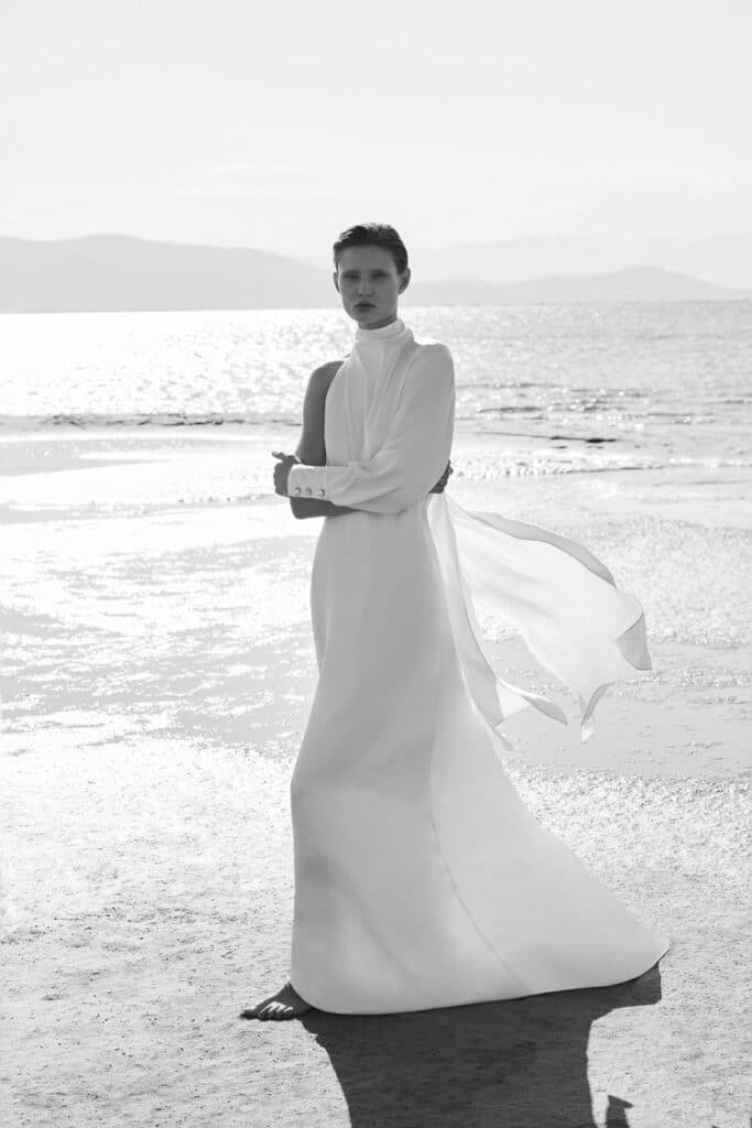 A-symmetrical long bridal gown with e long sleeve with cuff, small standing collar and slightly flared skirt.