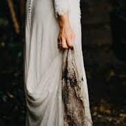 Foto einer Braut, die ihr Kleid hochhält, dessen innerer Boden sehr schmutzig ist